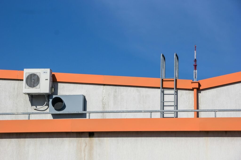 Rooftop view with HVAC unit, ladder, and clear sky background.